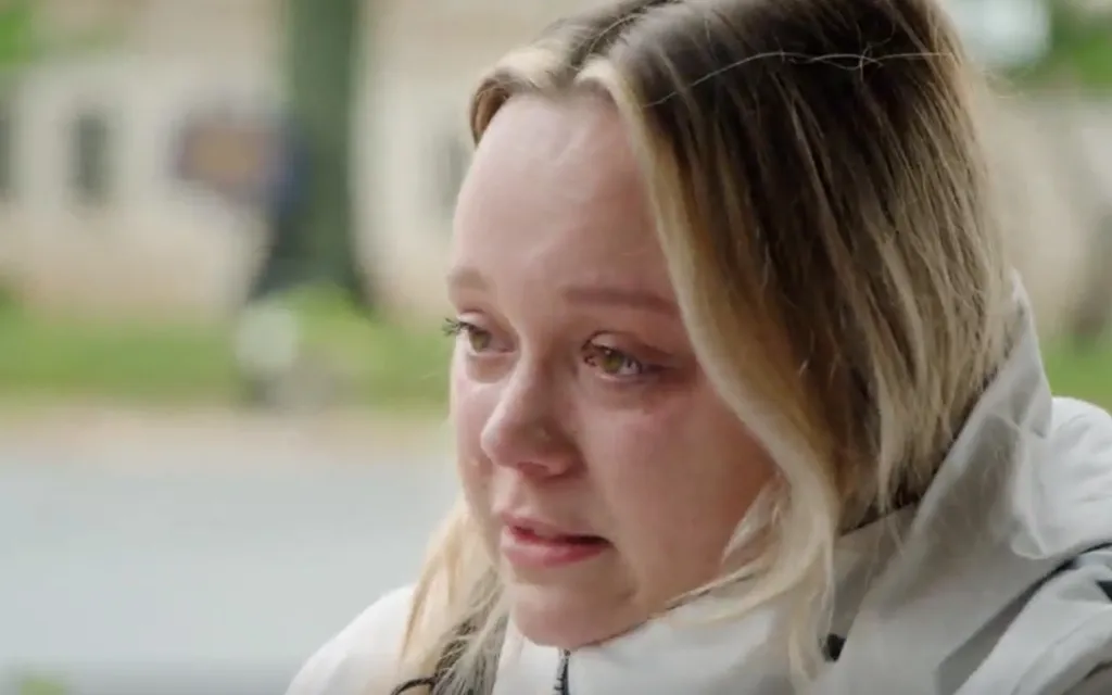 A crying blonde woman with green eyes, looking distressed.