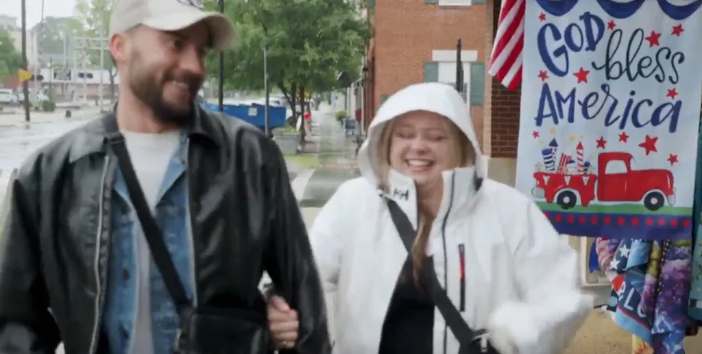 Rasit and Mallorie smiling while walking down a street in the rain.
