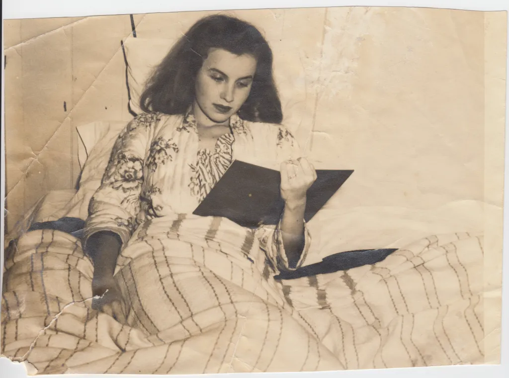 A woman in a floral robe reads in bed.