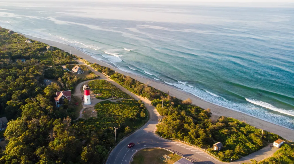 Aerial view of Nauset Beach with the Nauset Light, a red and white lighthouse, on the coastline.