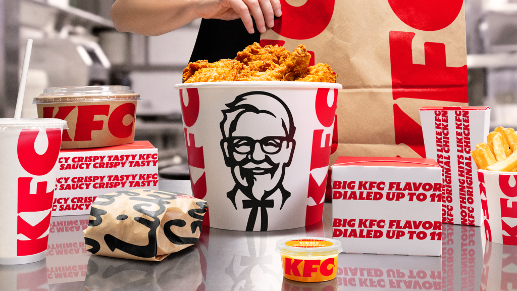 A bucket of KFC fried chicken, a drink, fries, and other KFC packaging.