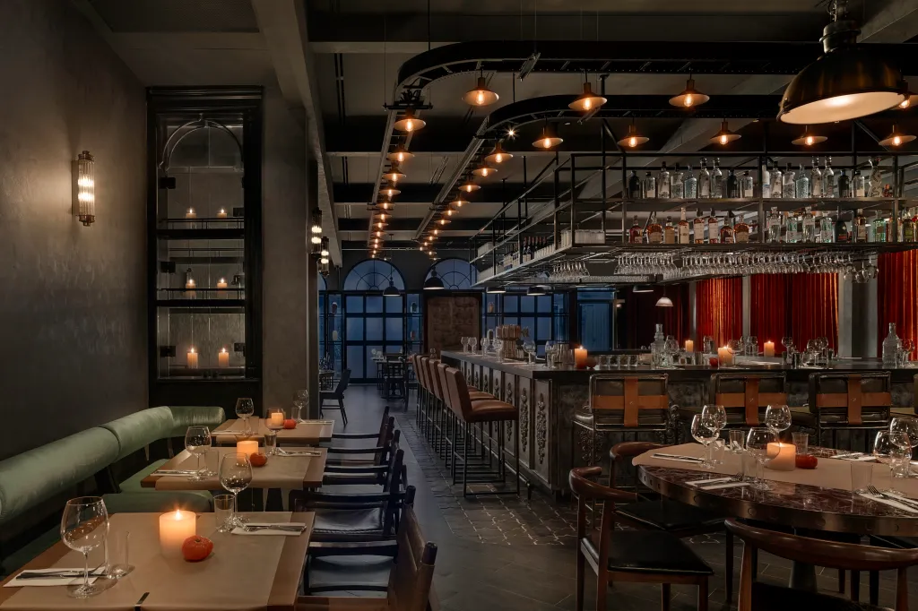 Dining room with a long bar to the right and tables with chairs to the left.