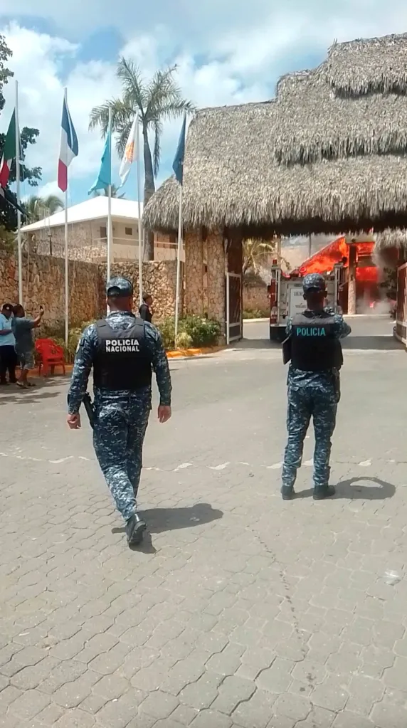 Police officers outside a resort building engulfed in flames.