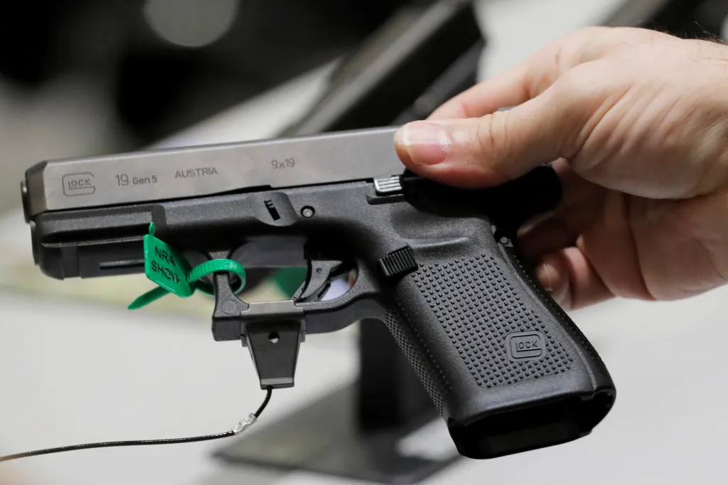 A man holding a Glock handgun with a green