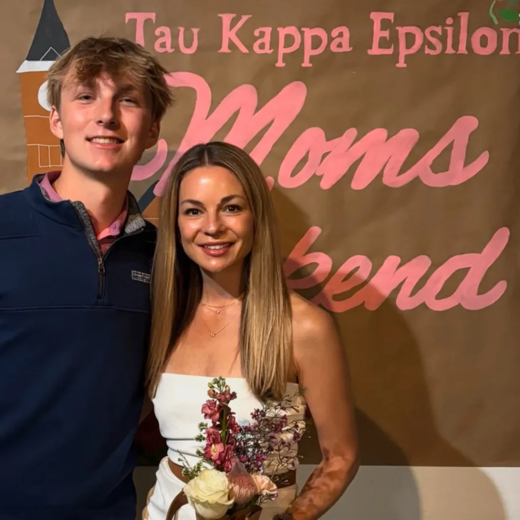 A man and a woman stand in front of a banner that reads 