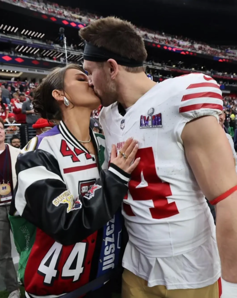 A man in a football uniform kissing a woman wearing a matching jacket.
