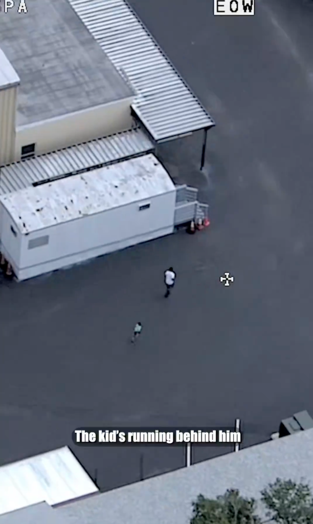The young boy follows Kenon through a parking lot as a police helicopter tracks their movement.