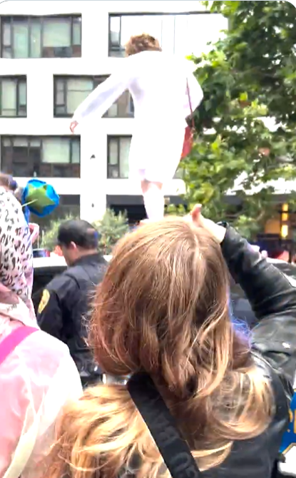 Person in white clothing on shoulders of someone in a crowd.