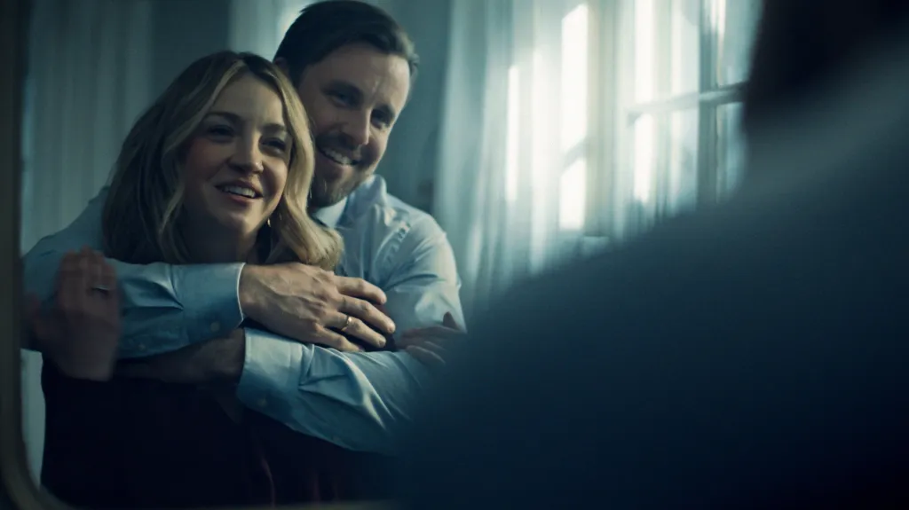 Abby Elliott and Chris Witaske smile, embraced from behind by a third person, in a scene from 