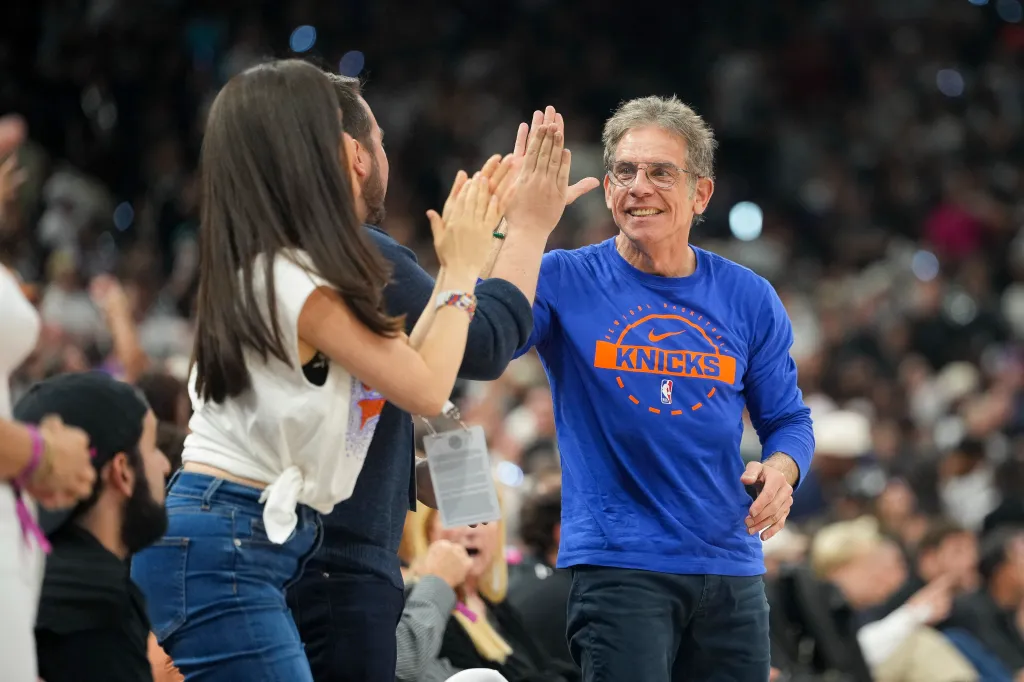 Ben Stiller high-fiving a woman while wearing a New York Knicks shirt at an NBA Finals game.