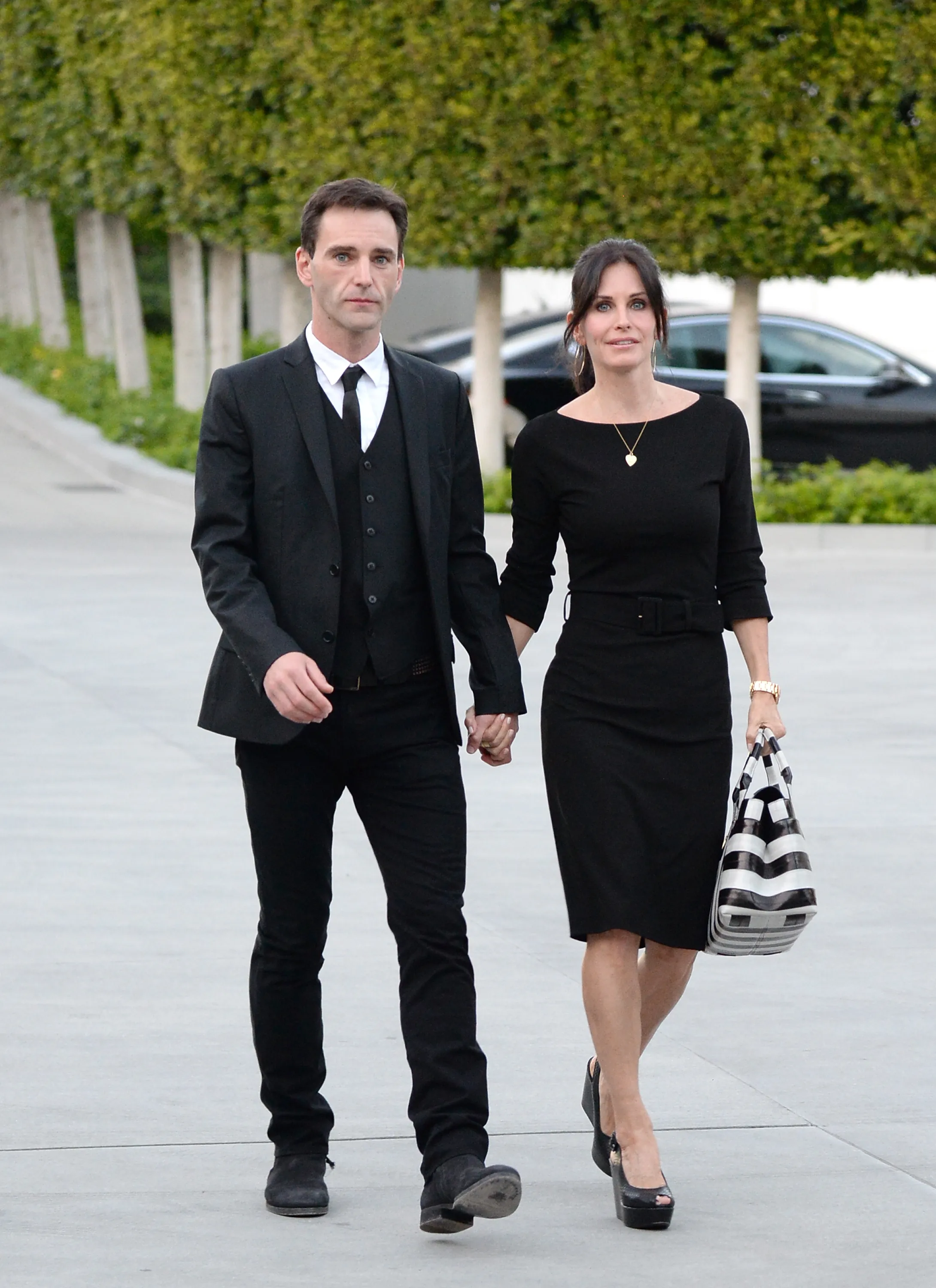 Courteney Cox and Johnny McDaid walking hand in hand at an environmental event.