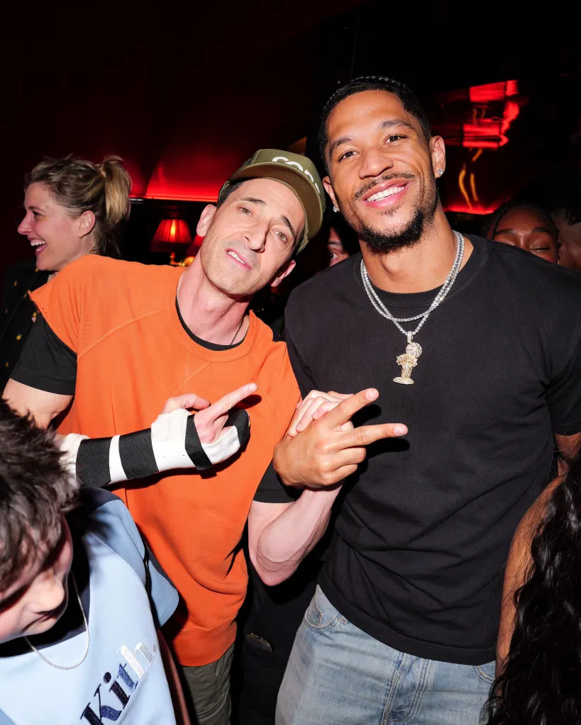 Adrien Brody wearing a wrist brace and Josh Hart smiling at the Knicks' post-parade celebration.
