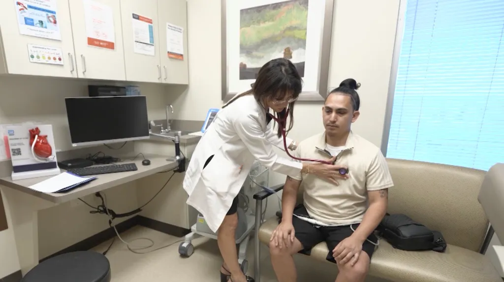 Doctor examining patient Alex Balmes with a stethoscope.
