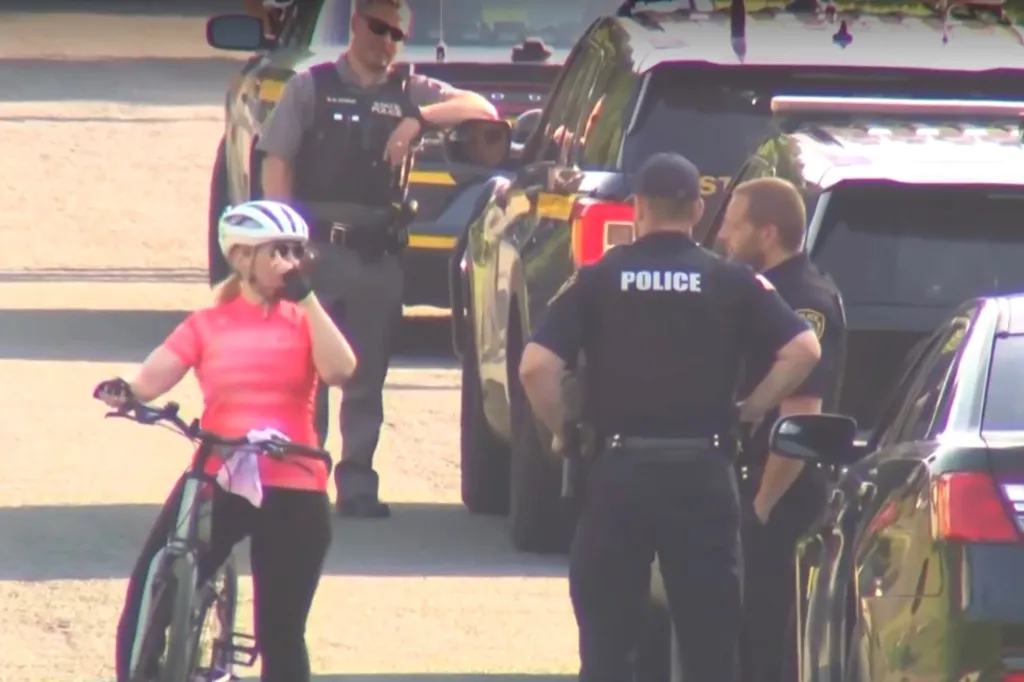 Police officers conducting search operations for a missing 7-year-old child, with a person on a bicycle in the foreground.