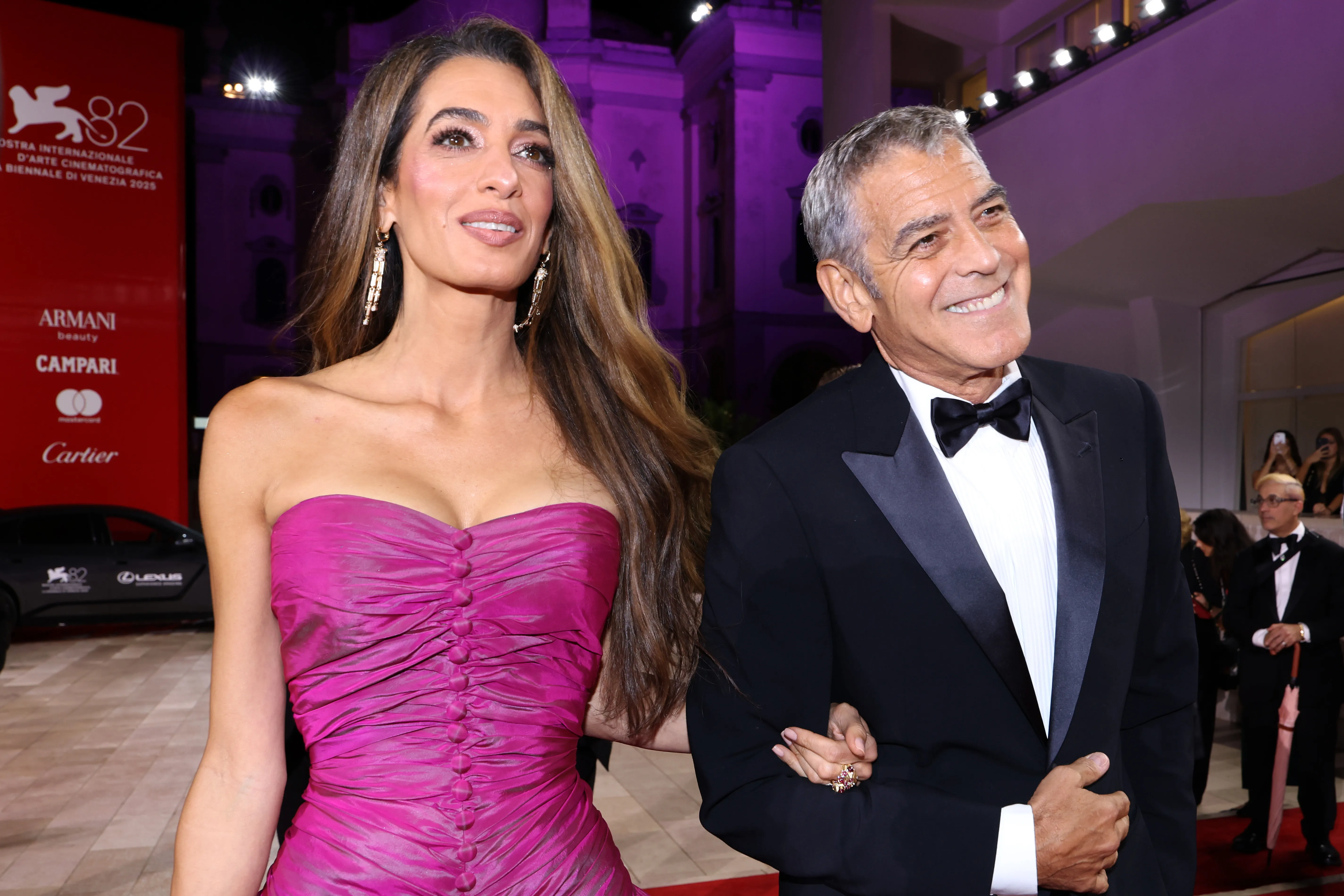 Amal Clooney in a pink gown with George Clooney in a tuxedo at the 82nd Venice International Film Festival.