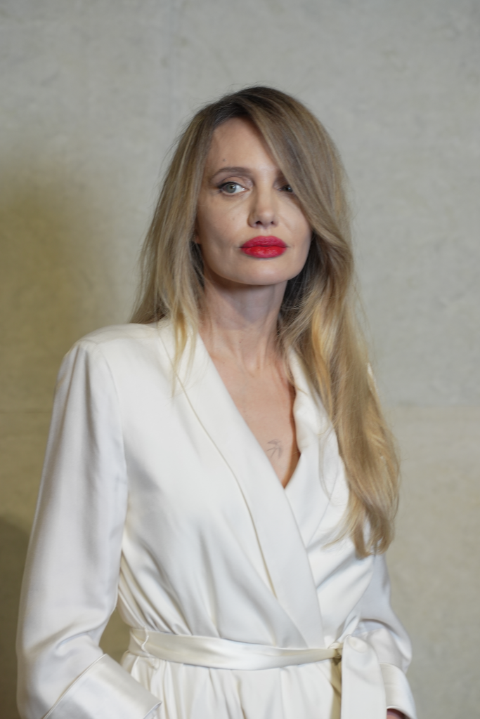 Angelina Jolie in a white outfit with a red lip attends a Tom Ford event.