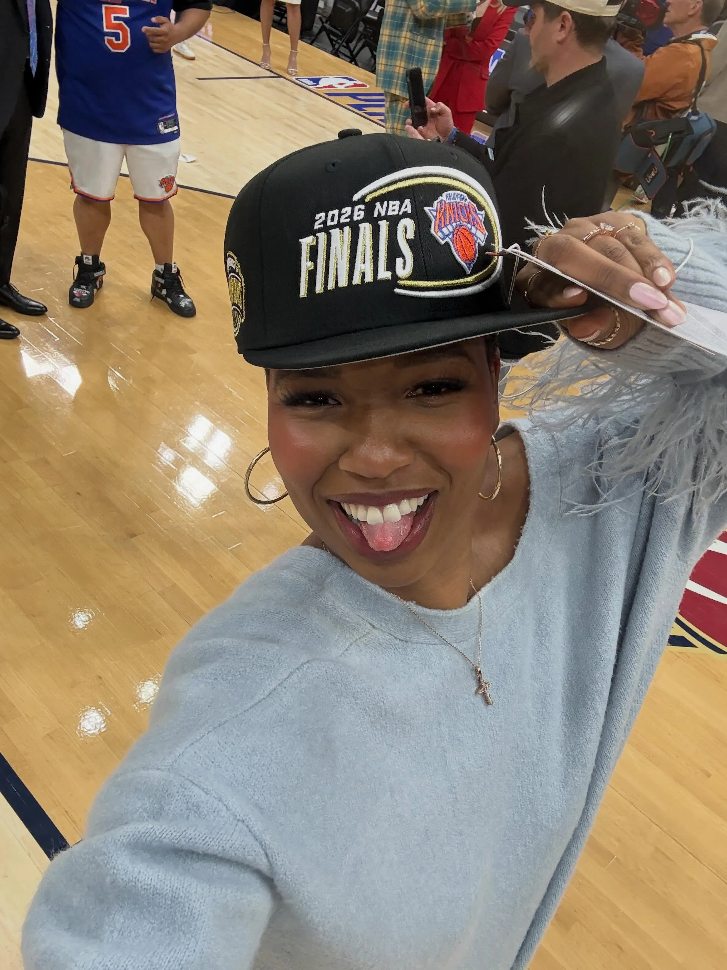 Monica McNutt smiling and holding a black cap that says 