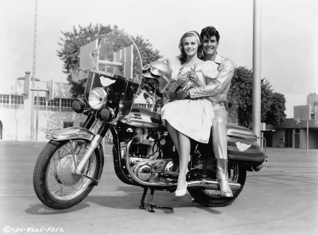 Ann-Margret as Kim McAfee and Jesse Pearson as Conrad Birdie on a motorcycle in a film still from the 1963 film 