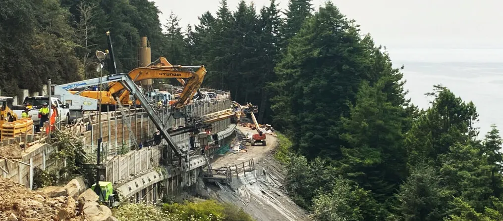 Construction workers building a new road section along an unstable stretch of the Pacific coastline.