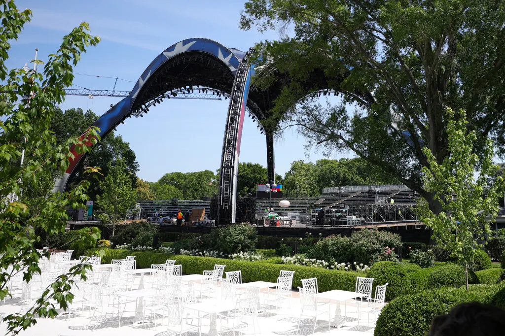 An event arena with a large arched stage and bleachers, seen from the Rose Garden.