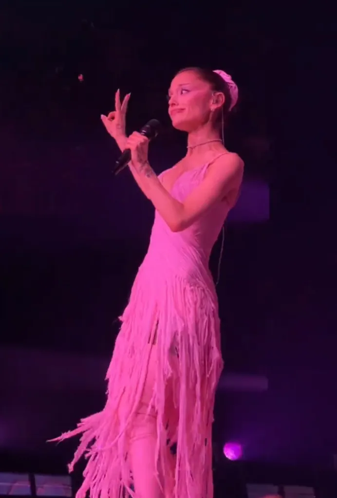 Ariana Grande in a shredded pink dress making an 
