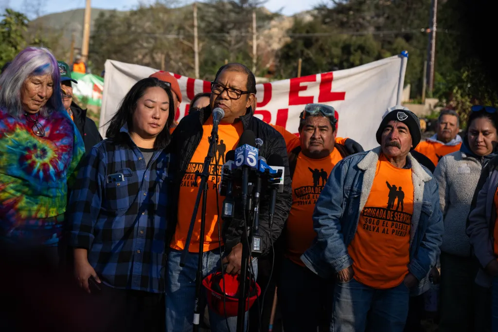 Pablo Alvarado, co-executive director of National Day Laborer Organizing Network, speaks to the press alongside artist Leigh Adams and Enji Chung of the Fire Poppy Project.