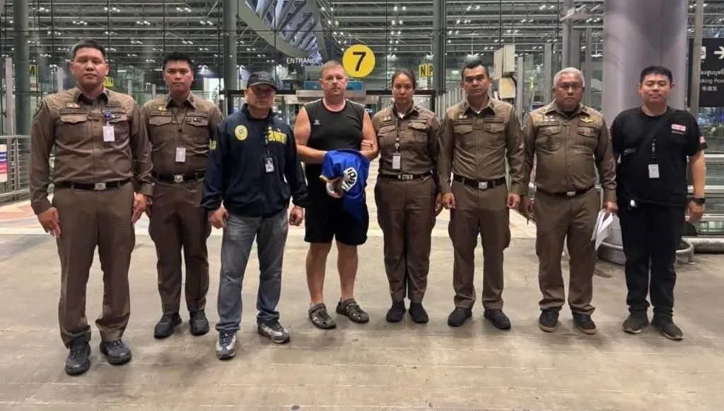 An Australian man arrested at a Thai airport is surrounded by Thai police and officials.