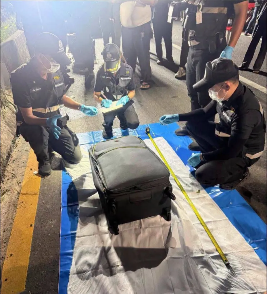 Law enforcement officers examine a suitcase at an airport.