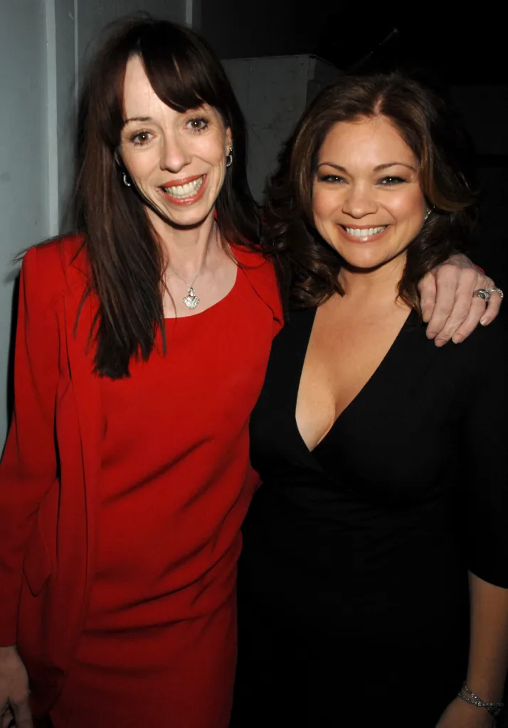 Mackenzie Phillips in a red dress with a heart necklace and Valerie Bertinelli in a black dress with her arm around Phillips, both smiling for a photo.