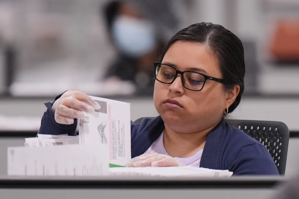 A woman wearing glasses and gloves inspecting ballots.