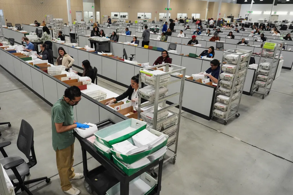 Workers in a large hall inspect ballots the day after California's primary election.