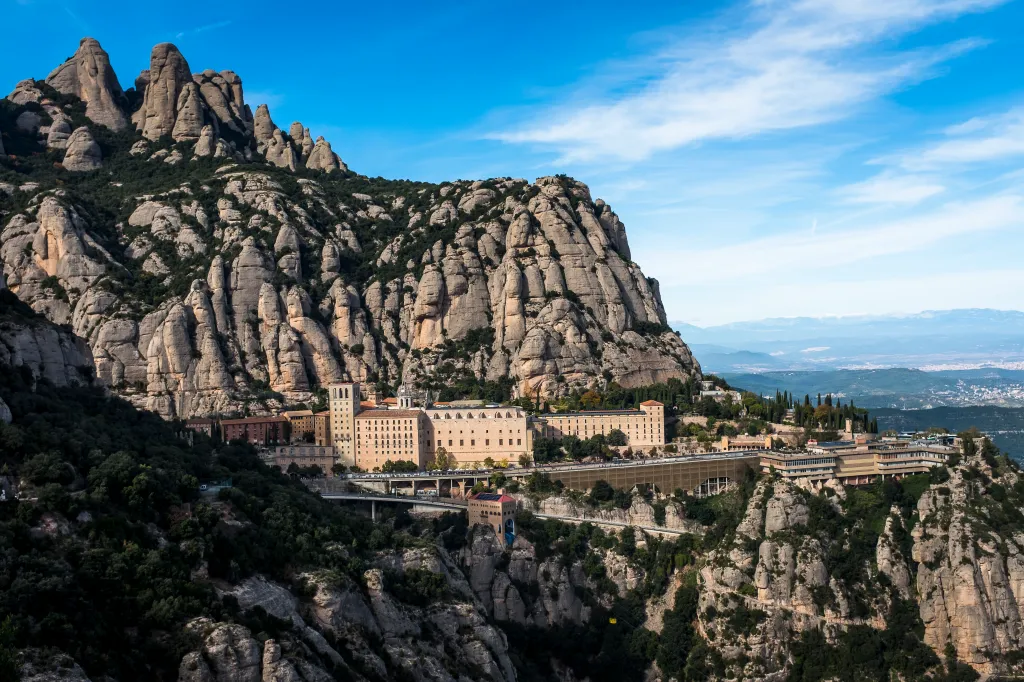 The Basilica of Santa Maria of Montserrat and surrounding buildings nestled into the rocky Montserrat mountains.