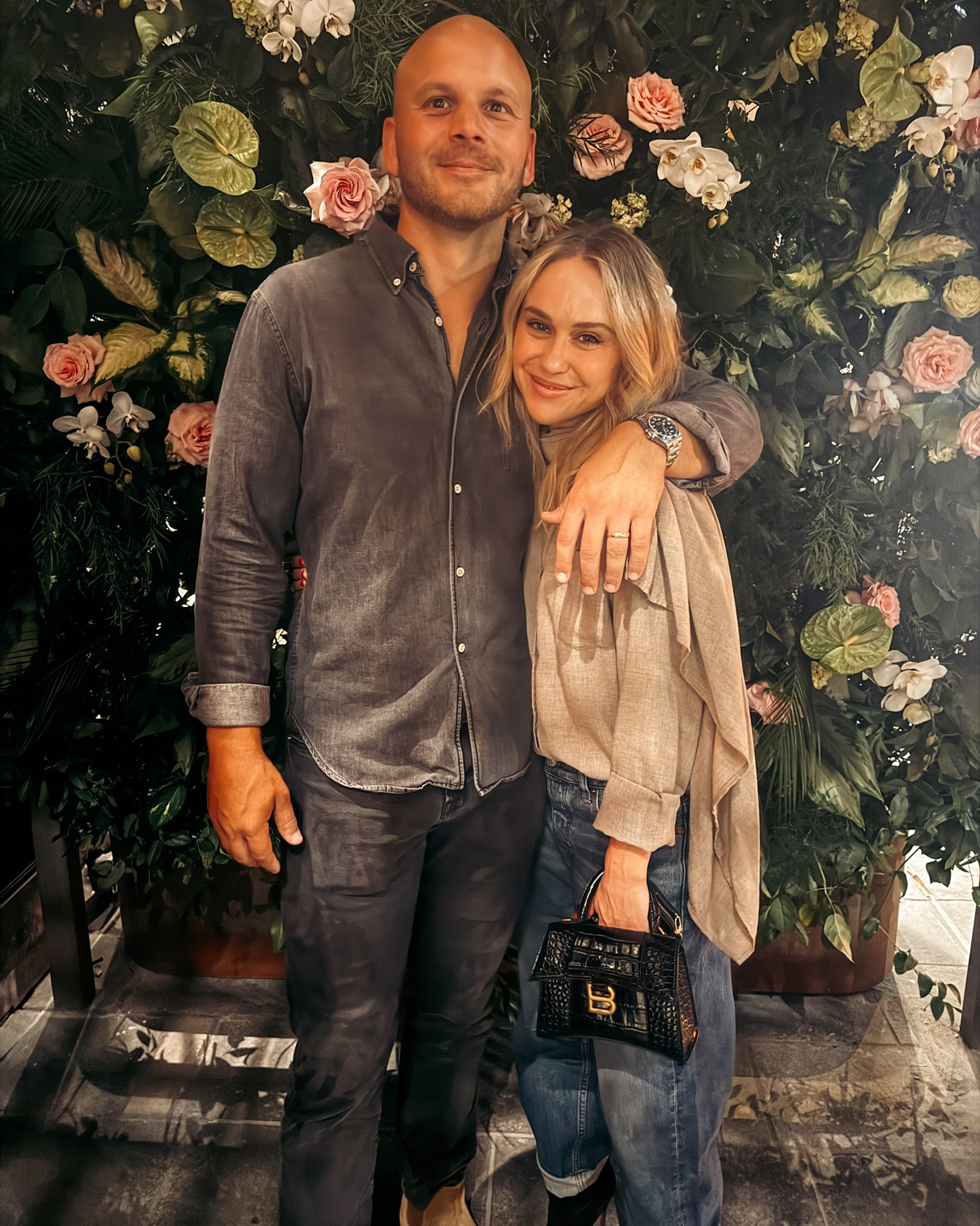 Becca Tobin and Zach Martin standing in front of a floral background.