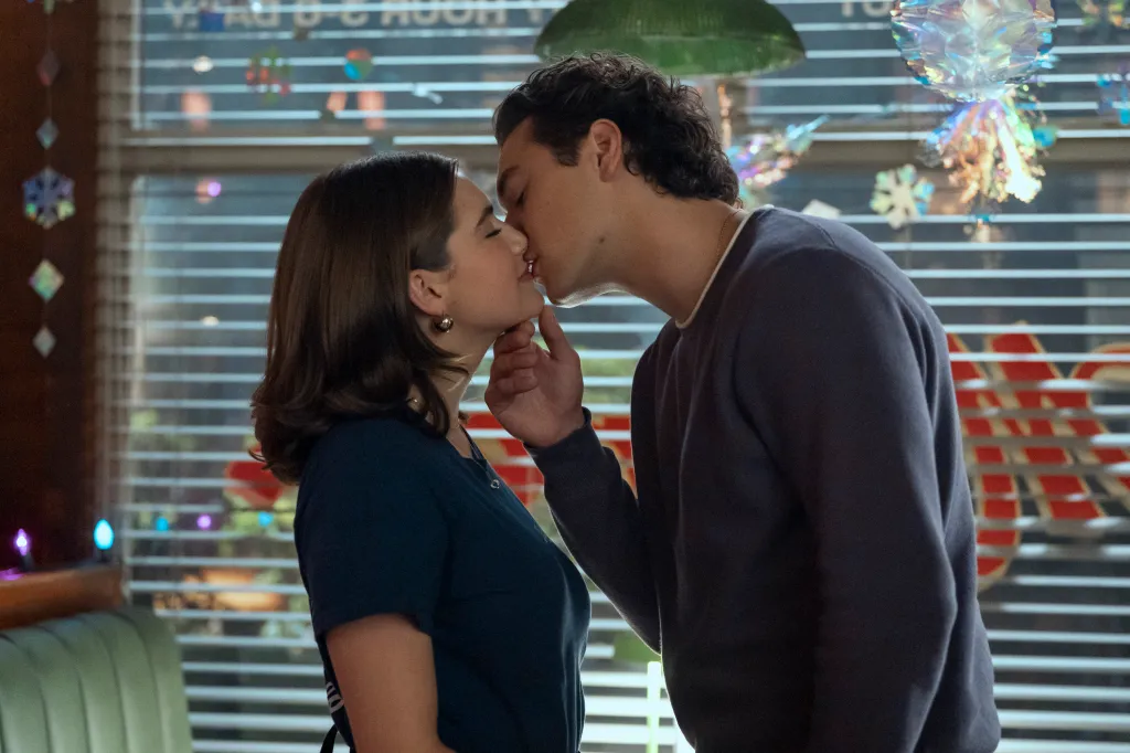 Belmont Cameli and Ella Bright sharing a kiss in a diner.