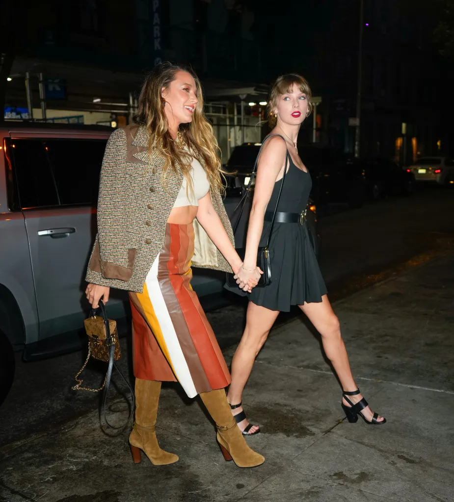 Blake Lively and Taylor Swift walking down the street at night, holding hands.