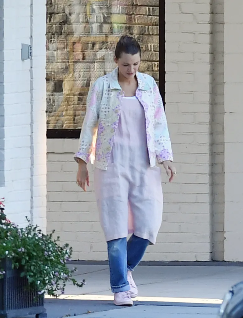 Blake Lively grocery shopping, wearing a patterned jacket, pink dress, jeans, and pink trainers.