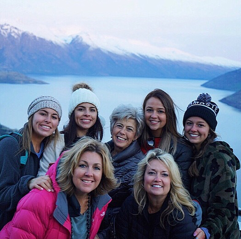 Brad Pitt's nieces, sister, sister-in-law, and mother posing outdoors with mountains and water in the background.