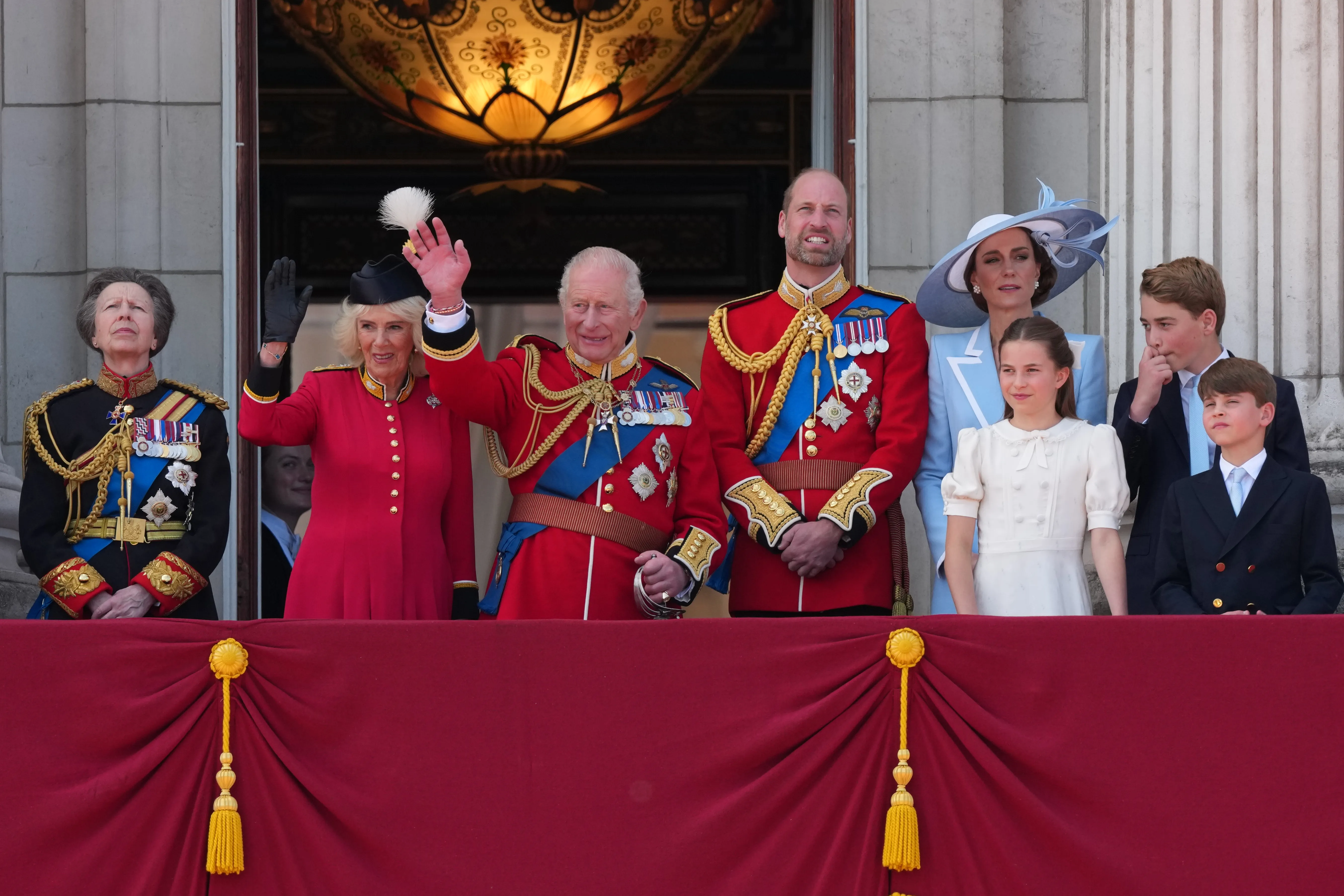 King Charles III waves to crowds from the Buckingham Palace balcony with royal family members during Trooping The Colour.