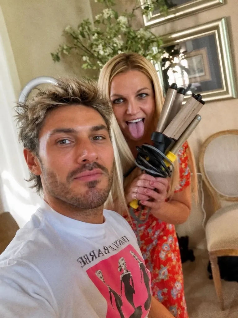 Britney Spears playfully holding a hair crimper behind celebrity hairstylist Chris Appleton.