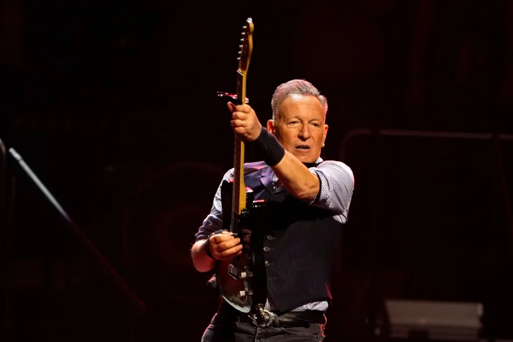 Bruce Springsteen holding up his guitar during a performance.