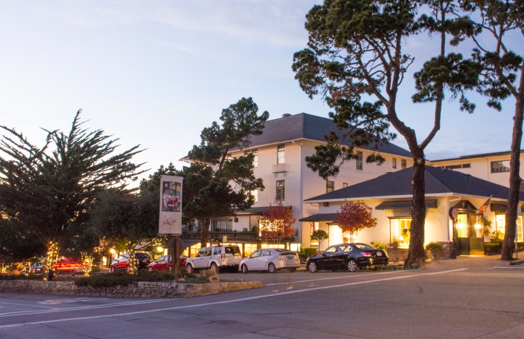 Ocean Avenue in Carmel, California at twilight, with buildings and shops illuminated.