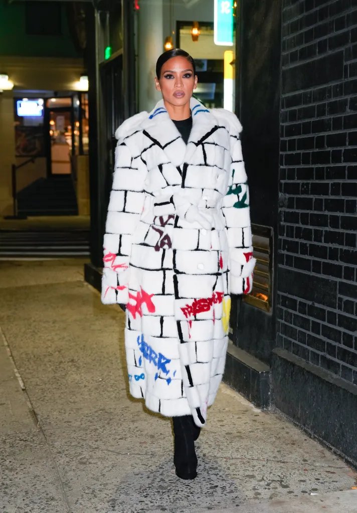 Cassie wearing a white Romeo Hunte coat with colorful graffiti-like designs.