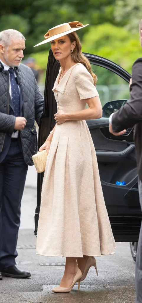 Catherine, Princess of Wales, stepping out of a car, wearing a cream dress and matching hat and heels.