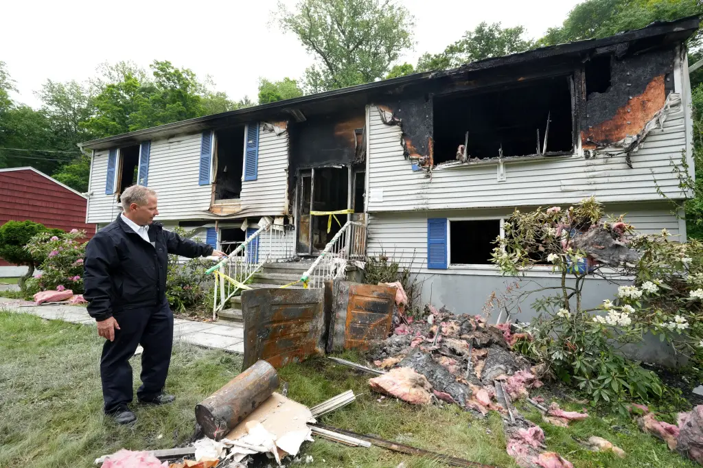 Chief Thomas Eade stands in front of a heavily damaged house after a structure fire.