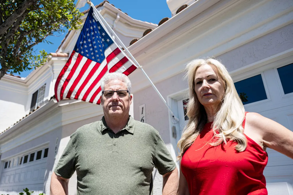 Chris and Amy Cooke standing in front of their home with an American flag displayed.