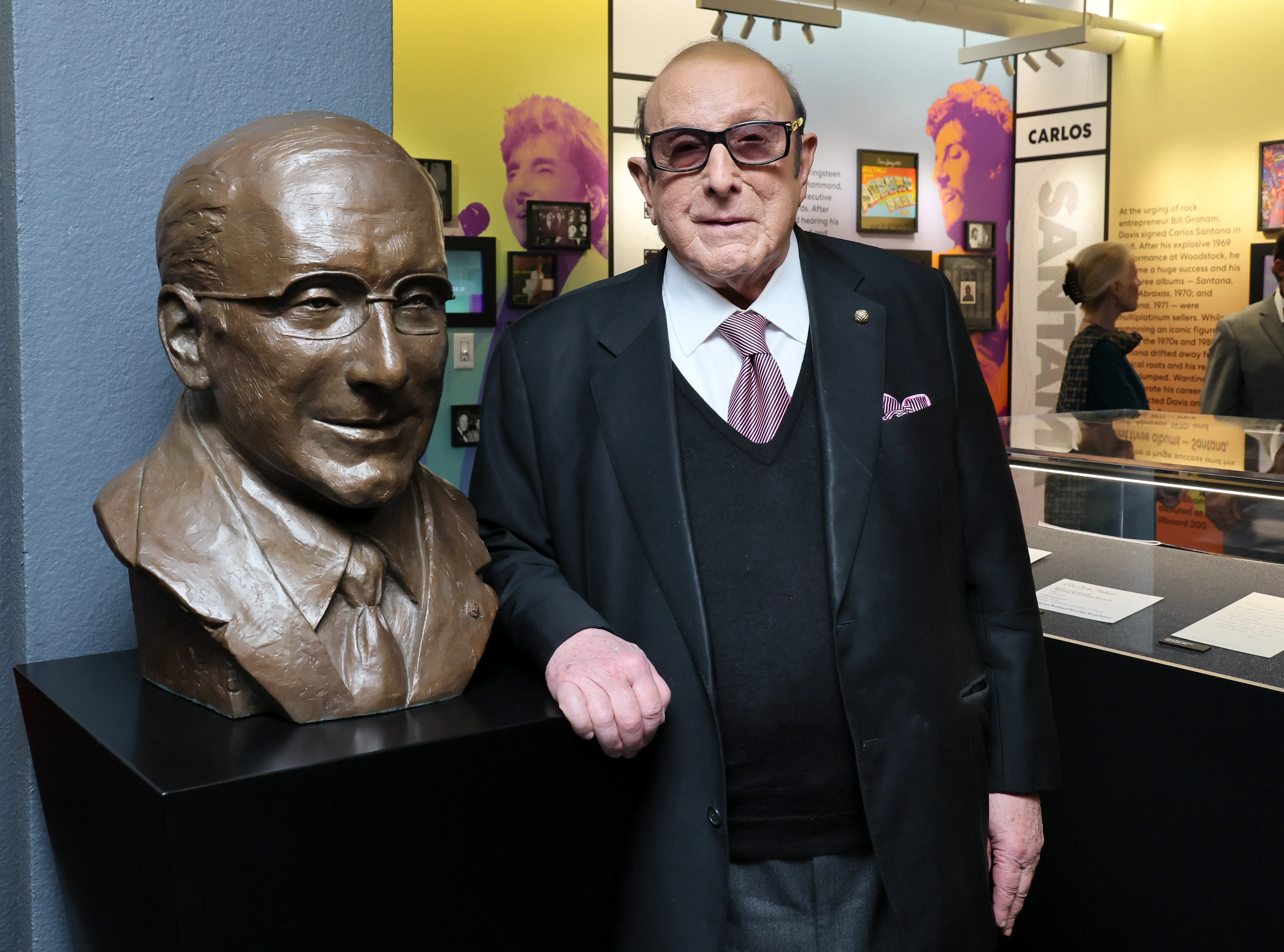 Clive Davis standing next to a bronze bust of himself at the Clive Davis Gallery Ribbon Cutting at New York University.
