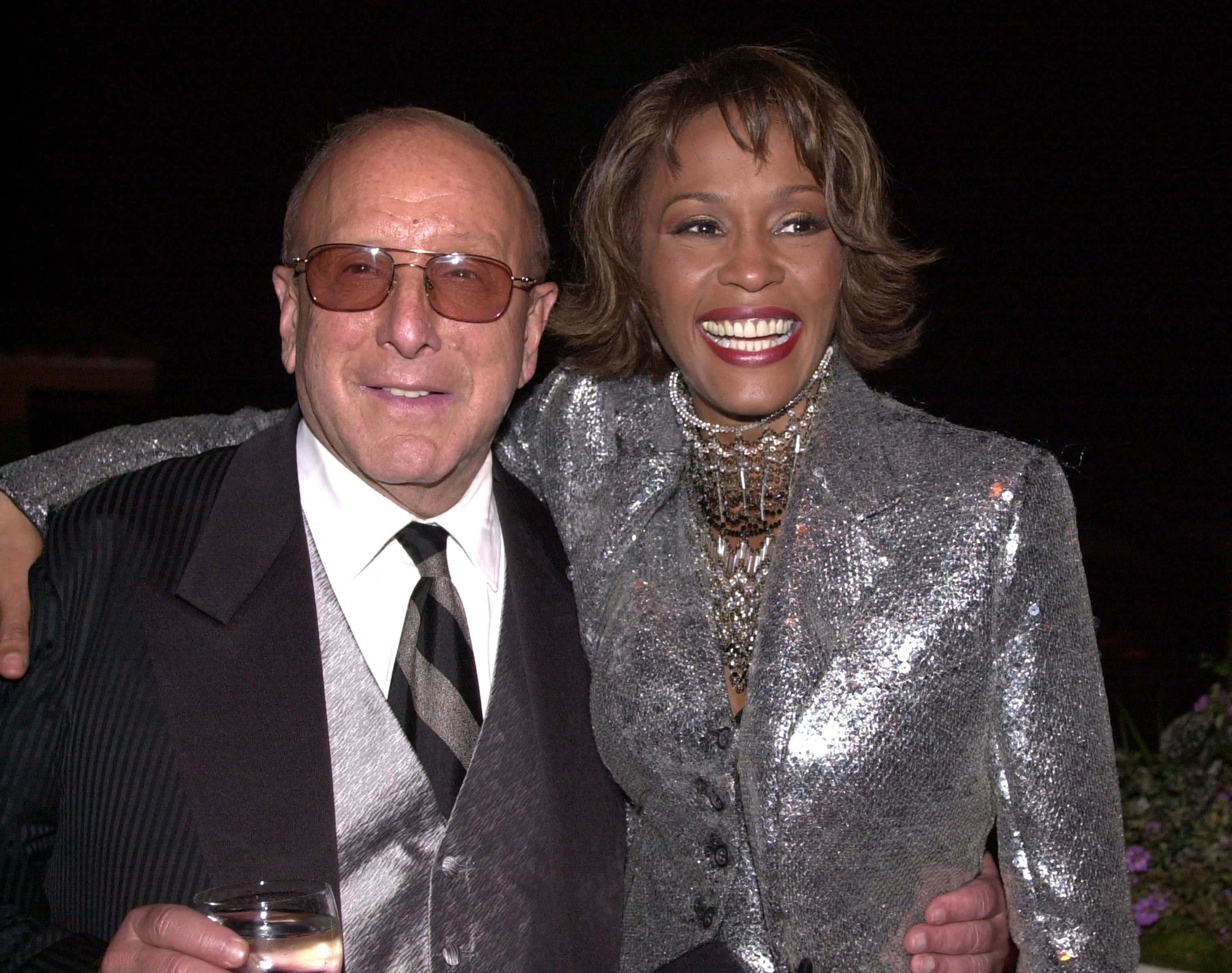 Clive Davis and Whitney Houston embracing and smiling at the Arista 25th Anniversary Celebration After Party.