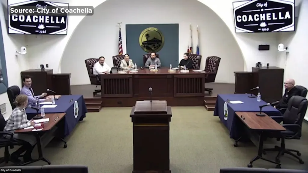 A City of Coachella council meeting with several members seated at a raised dais and two people seated at tables on the main floor.