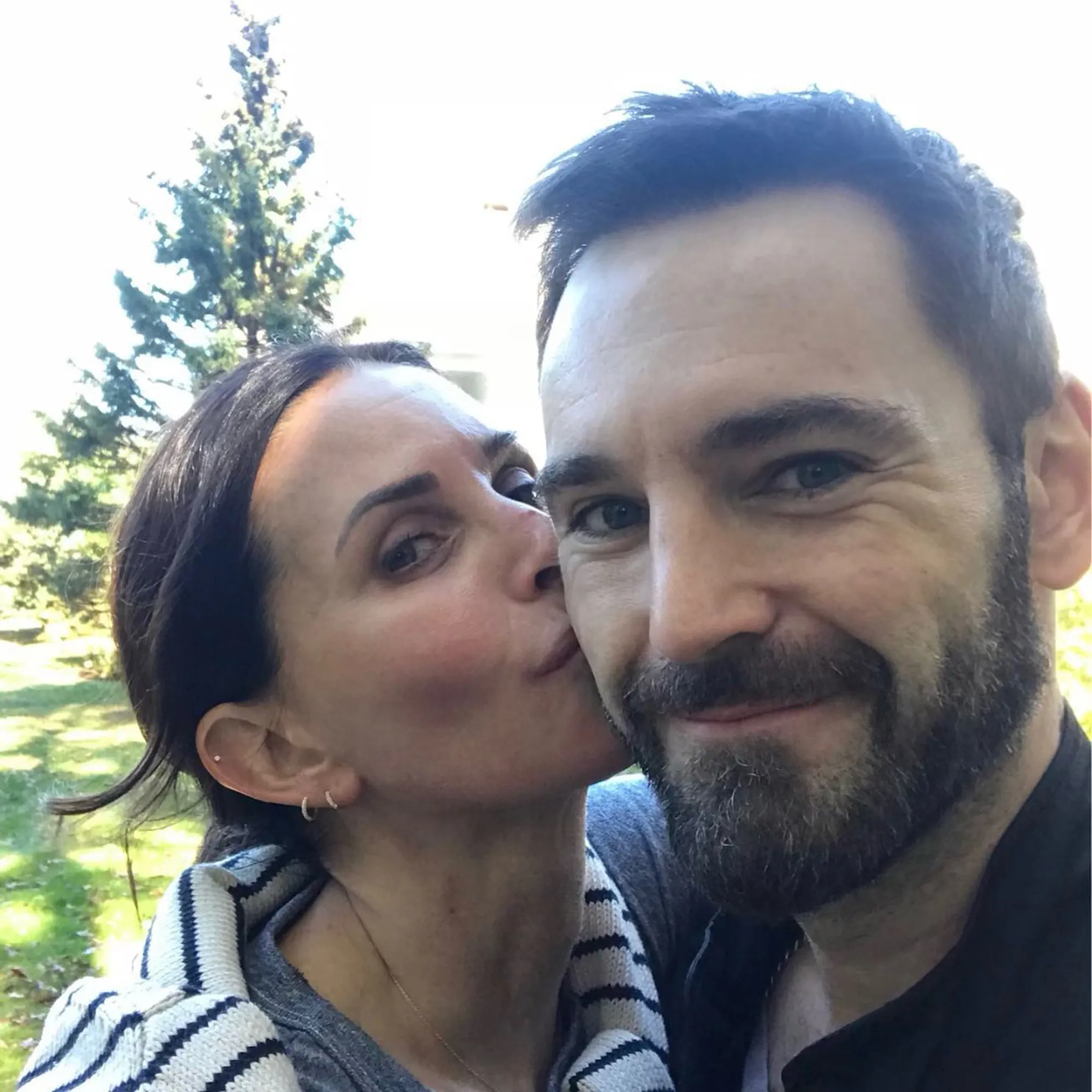 Courteney Cox kissing Johnny McDaid on the cheek.