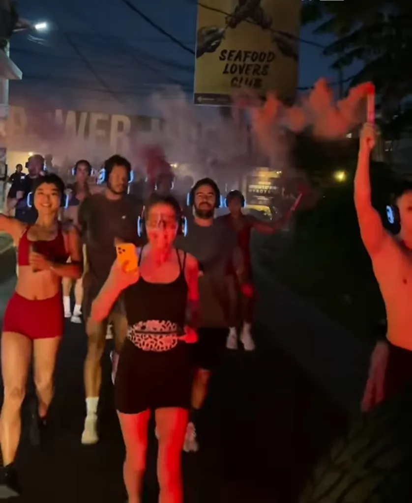 People running in a silent disco run in Bali with red smoke.
